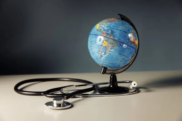 Globe with stethoscope on a grey background — Stock Photo, Image