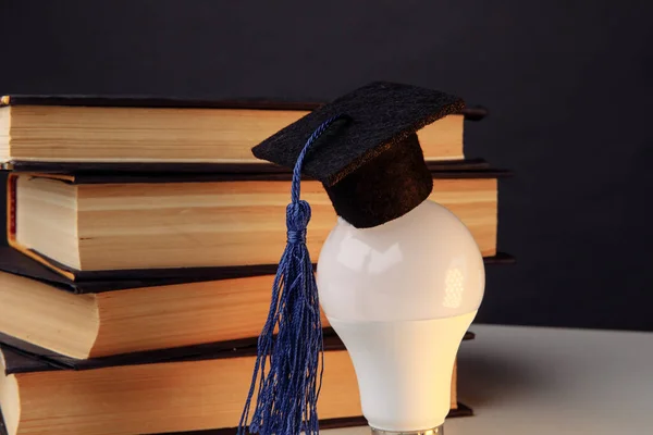 Graduation cap on light bulb with books close-up. Education idea — Stock Photo, Image