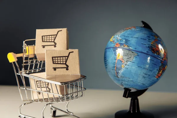 Globo y supermercado carrito de compras con cajas. Comercio mundial y entrega de compras — Foto de Stock