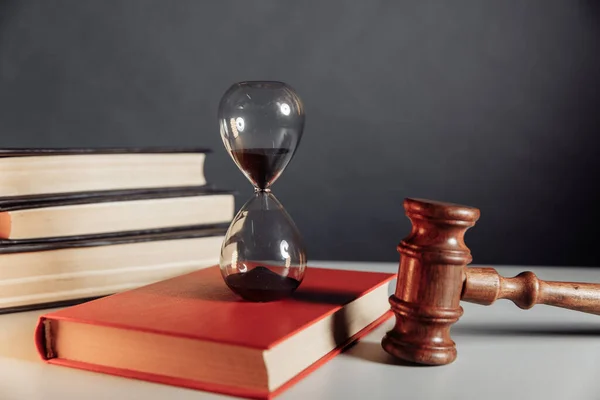 Concepto judicial. Reloj de arena en el libro y el martillo juez —  Fotos de Stock