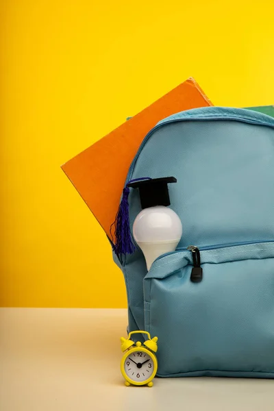 Яскравий рюкзак і лампочка. Концепція освіти. Вертикальне зображення — стокове фото