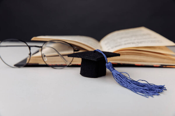 Graduation cap and glasses with open book
