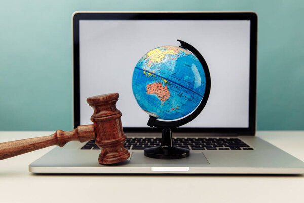 Wooden judge gavel and globe on laptop. International law concept