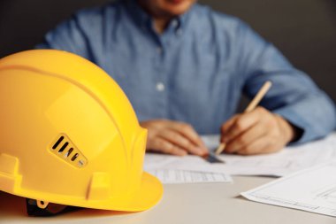 Planlar üzerinde çalışan mühendis, konsept inşa ediyor. Sarı miğferli işyeri mimarı