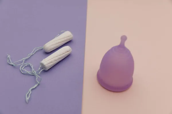 Tazza mestruale e tamponi su uno sfondo colorato. Concetto di igiene femminile — Foto Stock