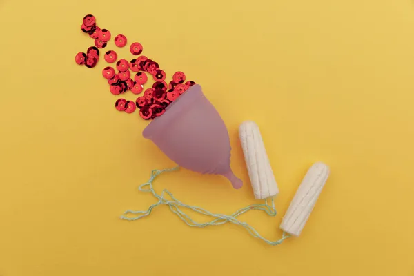 Tazza mestruale igienica con paillettes rosse e tamponi di cotone su fondo giallo. Modo alternativo di igiene femminile — Foto Stock
