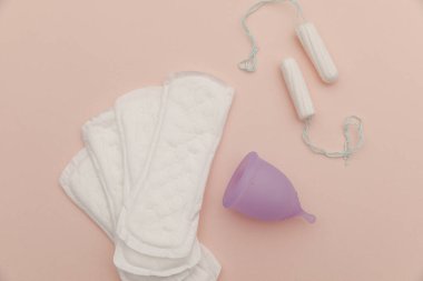 Pembe arka planda ped, regl kupası, tampon. Kadın hijyeni kavramı.