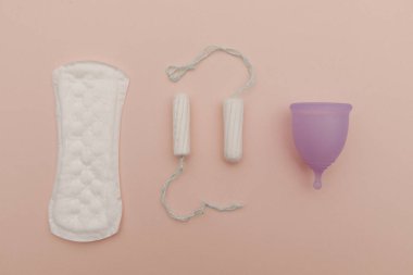 Pembe arka planda ped, regl kupası, tampon. Kritik günler ve kadın hijyeni kavramı. Üst görünüm