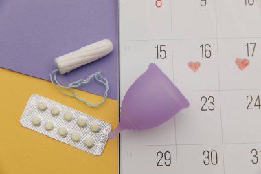 Takvim, tampon ve ağrı kesici haplı regl kupası. Kadın kritik günler ve hijyen koruması