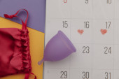 Kalendář a menstruační pohár s taškou zblízka. Žena kritické dny a ochrana hygieny