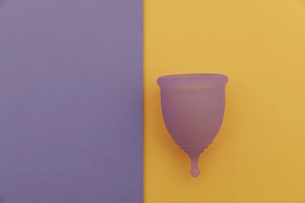 Purple menstrual cup on a colorful background close-up. Alternative way of womens hygiene — стоковое фото