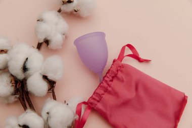 Pembe arkaplanlı, yeniden kullanılabilir, mor regl kupası. Üst Manzara. Çevre dostu ve modern kadın hijyen kavramı.
