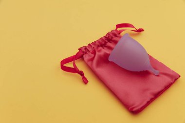 Sarı arka planda regl fincanı ve çanta. Ekoloji ve geri dönüşüm kavramı