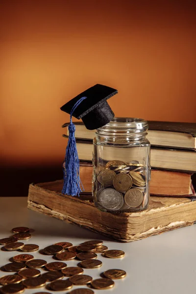 Stock image Glass jar with coins with graduation hat on books, back to school concept