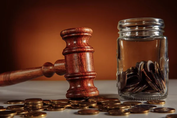 Coins in a glass jar and gavel close-up — Stock Photo, Image