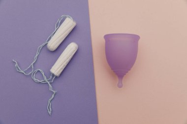 Renkli bir arka planda regl bardağı ve tampon. Kadın hijyeni ve sağlık hizmetleri kavramı
