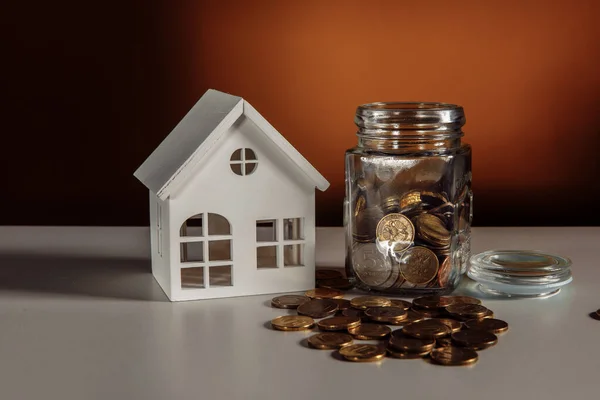 Modelo de casa y tarro con monedas, concepto de ahorro financiero y monetario — Foto de Stock
