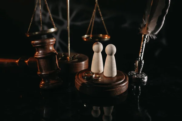 Ley y Justicia. Imagen vertical del martillo del juez, figuras de madera y anillos de bodas —  Fotos de Stock