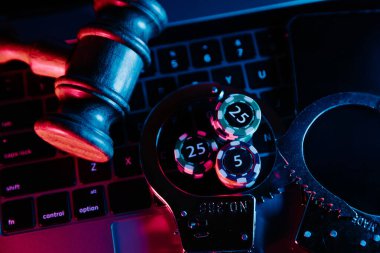 Hukuk ve yasadışı online kumarhane. Tahta tokmak, kelepçe ve yakın plan klavyede çip.