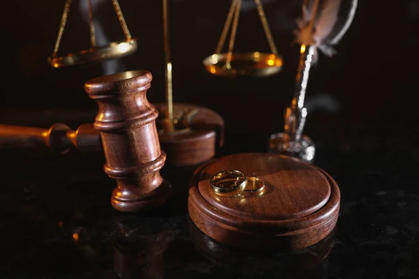 Conceito de divórcio e direito. Martelo juiz e anéis de ouro em uma mesa brilhante — Fotografia de Stock
