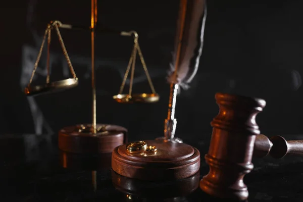 Концепция развода и права. Судья молоток и золотые кольца на глянцевом столе — стоковое фото