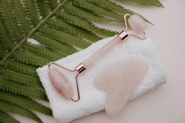 Pembe arka planda paten ve gua sha masaj kazıyıcısı. Bencillik, güzellik ve sağlık konsepti.