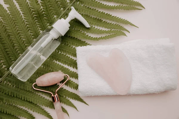 Yeşim yüzlü silindir ve eğrelti otu yapraklı havluyla guasha. Scin bakım konsepti