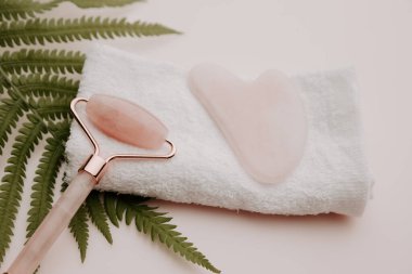 Güzellik konsepti. Gua sha ve masaj silindiri bir havlu ve eğreltiotu üzerinde