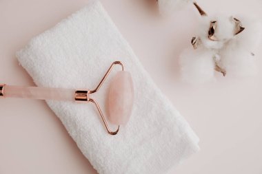 Pembe arka planda havlusu olan yeşim bir yüz silindiri, yüz terapisi konsepti