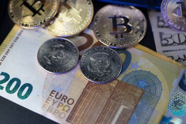 200 Euro 'luk banknotların ve yarım dolar bozuklukların üstüne Bitcoin. Çeşitli para birimleri, Avrupa, ABD ve sanal kripto para birimi