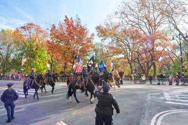 Manhattan, USA - 24. November 2021: Mounted Police holding flags in NYC during Thanksgiving Parade. NYPD riding horses at Macy's Parade, celebrating Thanksgiving
