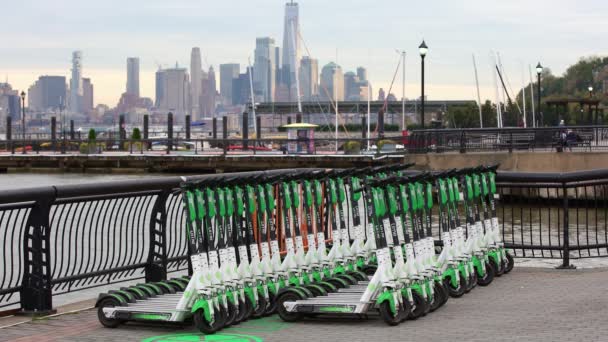 美国新泽西州霍博肯 11月5日 2019年 Lime Electric Scooter停放在新泽西州 以曼哈顿天际线为背景的绿色滑板车 曼哈顿下城和自由塔 — 图库视频影像