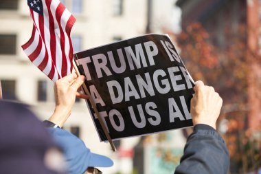 Manhattan, New York, ABD - 11 Kasım. 2019: Protestocu tabelası: New York 'taki Gaziler Günü Geçidi' nde düzenlenen bir pankartta Trump hepimiz için tehlike arz ediyor