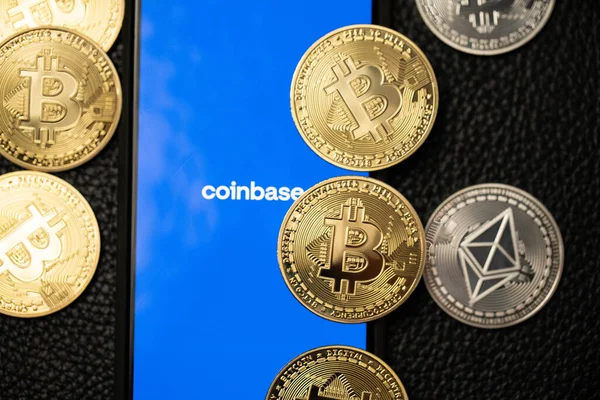 Bolzano, İtalya - 10 Nisan. 2021: Eter yüzeyinde bitcoin ve ethereum bozukluklarının yanında akıllı telefondan çalışan bozuk para uygulaması. Kripto para birimi ticareti için para tabanı uygulaması.