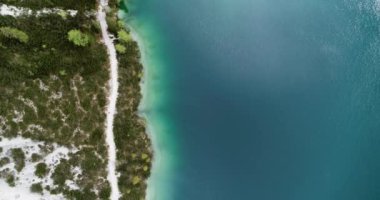 Çok güzel bir alp gölü. Dolomitlerdeki Pragser Wildsee. Turkuaz Suyu kıyısında yol. Dağlarda güzel bir arazide yürüyüş yapmak. 4K 'de İHA atışı. Egzotik beyaz kumlu plajlar