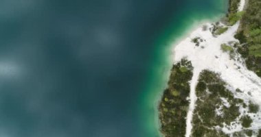 Dağlardaki Aerial Gölü. Alpine Gölü yukarıdan görünüyor. Kristal berrak su. Turkuaz suyu olan güzel bir sahil. Manzara üzerinde uçuyor. Göl kenarındaki yürüyüş yolu. 4K 'da üstten aşağı görünüm