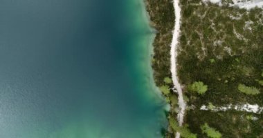 Aerial Gölü, İHA görüşü. Ormanla çevrili güzel su ve beyaz plajlar. Doğa 'da açık hava aktiviteleri. Dolomitlerle göl boyunca yürüyüş ve yürüyüş yolu. 4K 'da hava manzarası