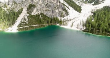 Hava Dağları manzarası, Alpler 'deki dik kaya yüzeyi ile çevrili göl. Aerial Lake, Alpine view, white beach and Pine Trees on beautiful sand beach at Braies, South Tirol, İtalya. 4K