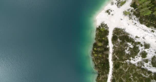 湖の上の小さなビーチの空中 空中海 原始的な澄んだ水と白い砂浜 イタリアのレイクブレイズ 4Kの上からの空中景観ビュー アウトドアアドベンチャーのための海岸沿いのハイキングパス — ストック動画