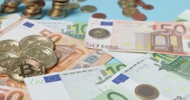 Altın Bitcoin paralar Euro banknotlarının üstüne ve arka planda Avrupa sikkeleri biriktirildi. Elli, iki yüz Euro 'luk banknotlar ve para birimleri. Crypto Cash ticareti kavramı