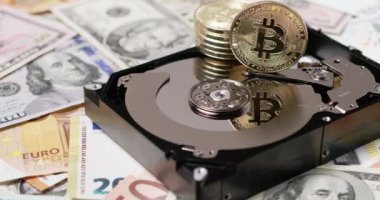 Hard Disk 'in üstünde Bitcoin, tepside yansıyan BTC madeni para. Arka planda Dolar ve Euro var. Bitcoin, Hırdavat 'ın üstüne yığıldı. Şifreleme ve depolama kavramı.