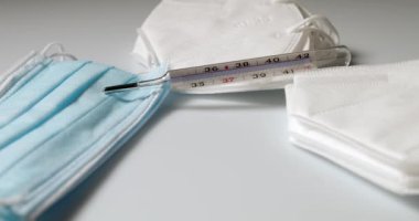 Doktor maskesi ve korona virüs koruması beyaz arka planda izole edildi. Tek kullanımlık yüz maskesi beyaz arkaplanda izole edildi. Plastik kulaklıklı cerrahi maske. Cerrahi maskeler ve ateş termometresi..