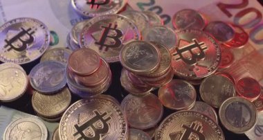 Banknotların üstüne yığılmış bozuk paralar, birikmiş Euro ve Bitcoin paraları. Avrupa 'daki kripto piyasaları, dijital varlıklar ve avro ile NFT ticareti