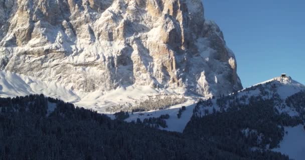 日の出 空中山の風景の間にアルプスのサッソルンゴ山 ヴァル ガーデナの森 太陽の木の山塊 そしてまだ早朝の影の中のスキー場を飛んでいます スキー場 — ストック動画
