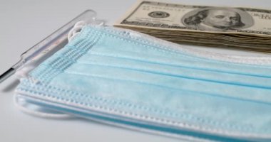 Sıcaklık ölçer, klinik maske ve yığınla dolar banknotları. 100 Dolarlık banknotlar, sağlık hizmetlerinin maliyeti sembolü