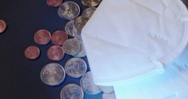 Beyaz KN95 Yüz Maskesi Altında Euro Sikkeleri. Avrupa Birliği 'nde ekonomik durgunluk, Covid 19' un neden olduğu sağlık felaketinin ardından