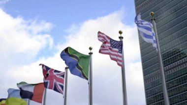 New York 'ta Birleşmiş Milletler önünde bayraklar. BM Binası önünde bayrak direğinde dalgalanan ABD, İngiltere, Tanzanya ve Uruguay bayrakları