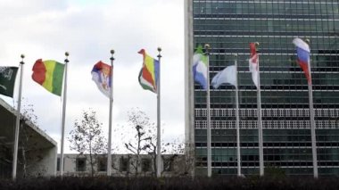 New York 'ta Birleşmiş Milletler önünde bayraklar. Rüzgarda dalgalanan ağır çekim bayrakları. Arka planda Sierra Leone bayrağı, Endonezya, Seyşeller ve Birleşmiş Milletler bayrağı