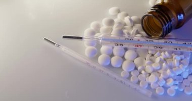 Beyaz hapların ve ilaçların üstüne termometre. Hastalık ve Hastalığın Teşhisi ve Tedavisi