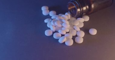 Şişede ağrı kesici, arka planda beyaz haplar. Cam bir kapta uyuşturucu ve yasadışı maddeler